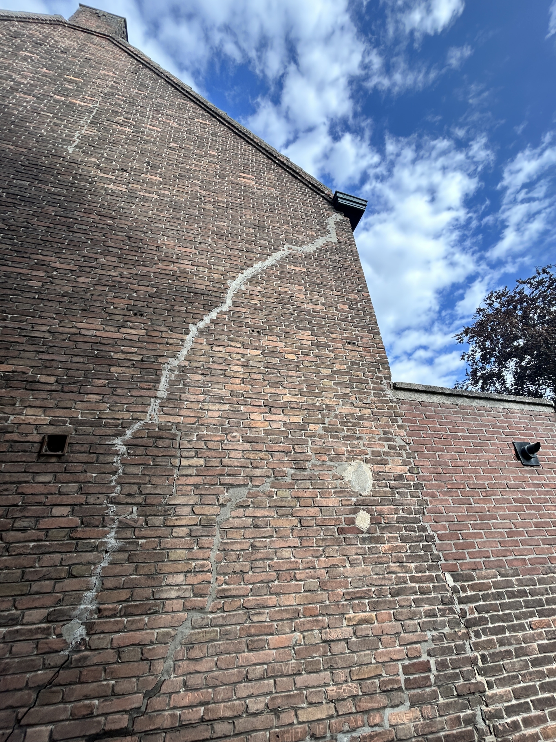 Trapsgewijze scheur in een bakstenen gevel als signaal van mogelijke funderingsproblemen