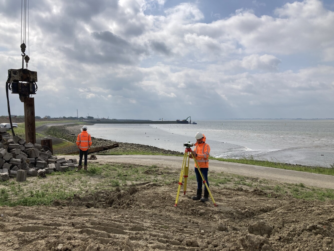 Landmeters van Quattro Expertise meten langs een dijk tijdens heiwerk