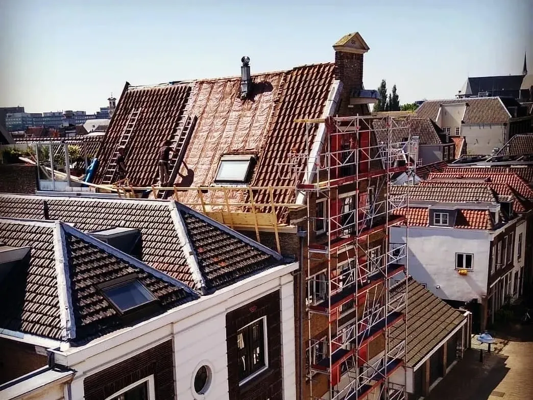 Daken van oude panden in Dordrecht met een steiger voor restauratiewerk